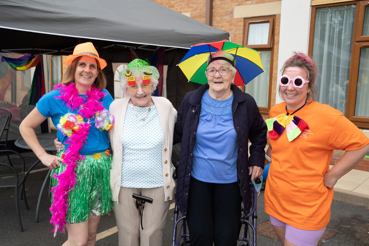 Four people wear rainbow-coloured items to celebrate Silver Pride at Fairway View care home in Nottingham