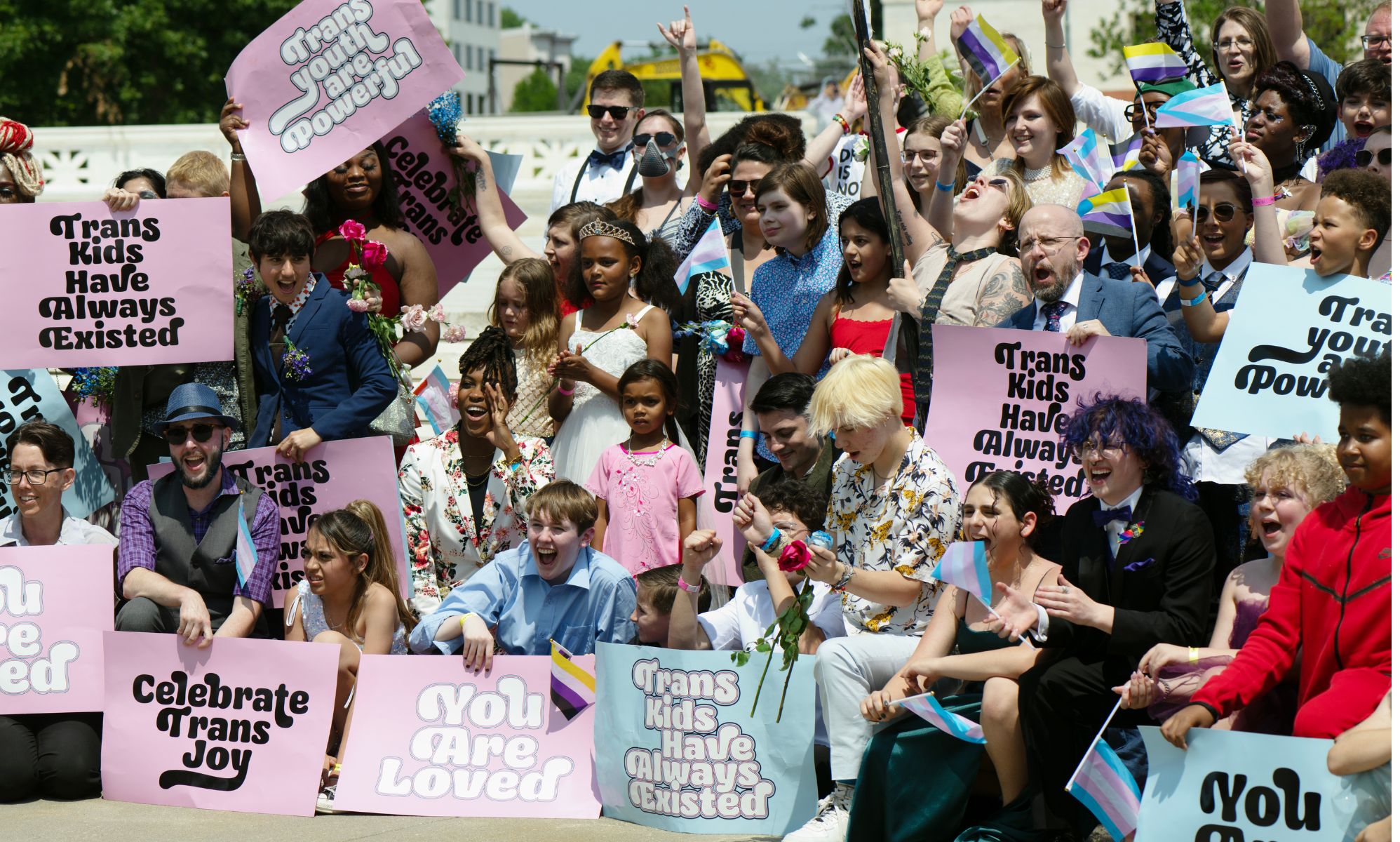 A group of trans youth hold signs of trans solidarity.