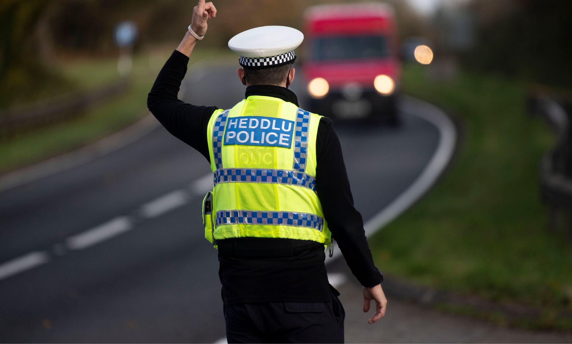 A Dyfed-Powys police officer stands by a nearby road.