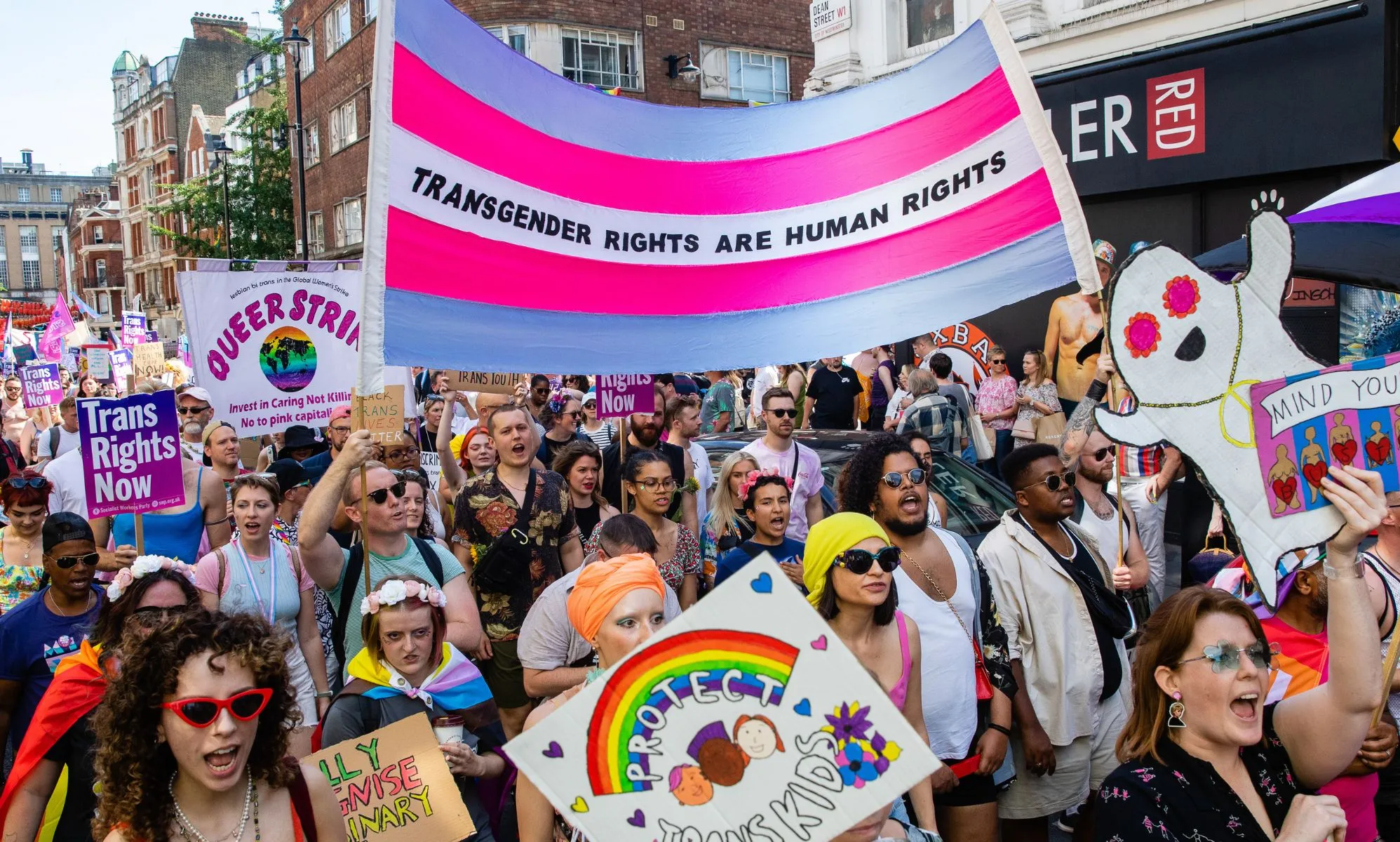 A crowd of people hold up a sign reading