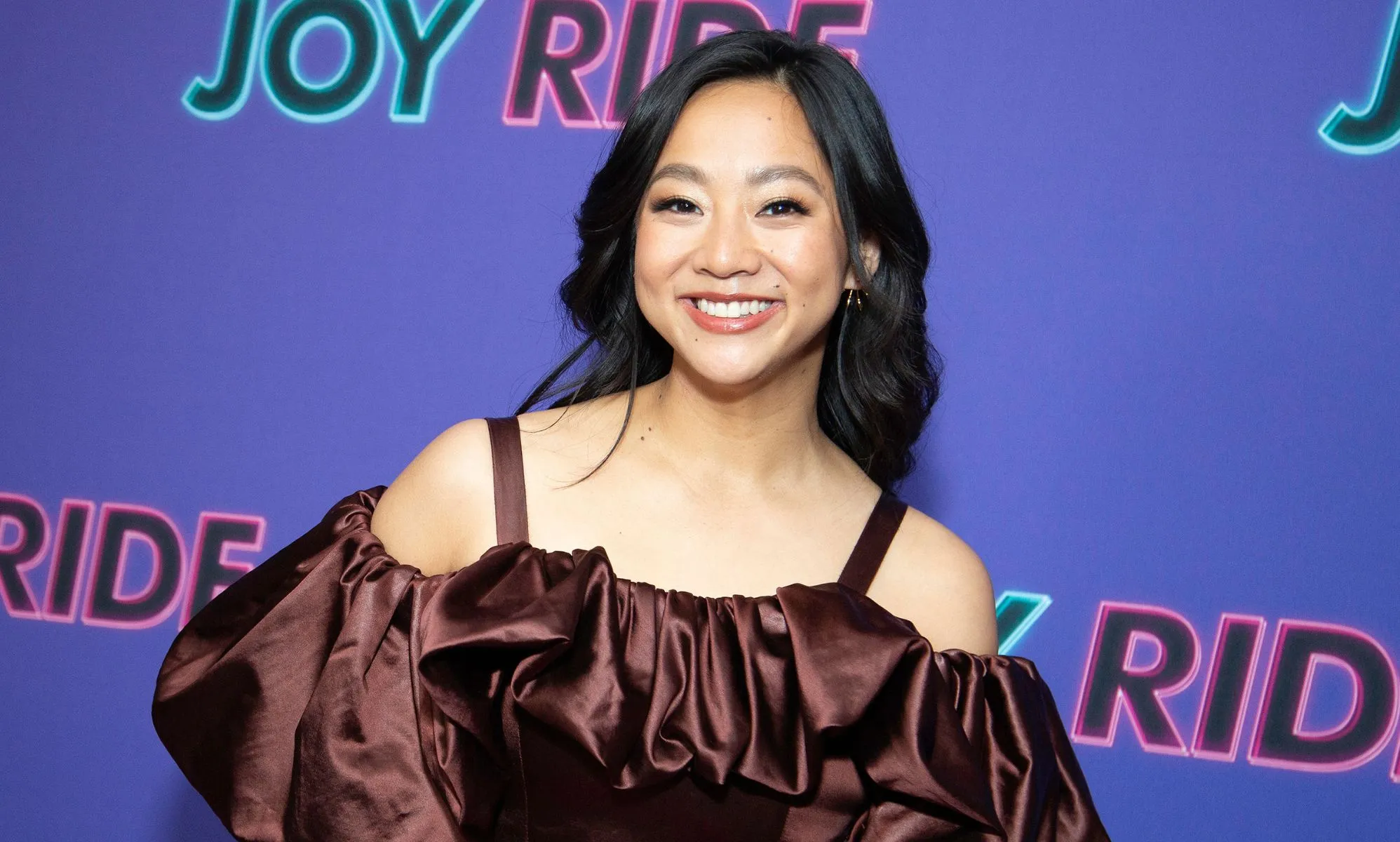 Stephanie Hsu in a poofy brown, off the shoulder dress.