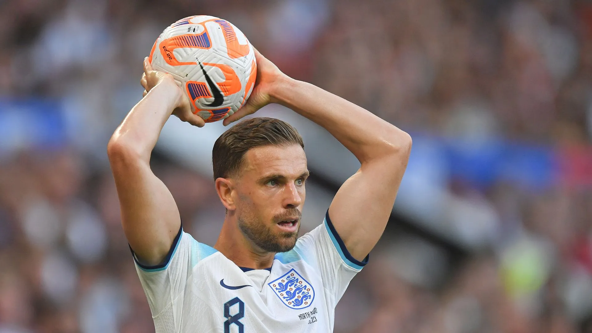 Footballer Jordan Henderson wears an England strip and gets ready to throw a football over his head during a match