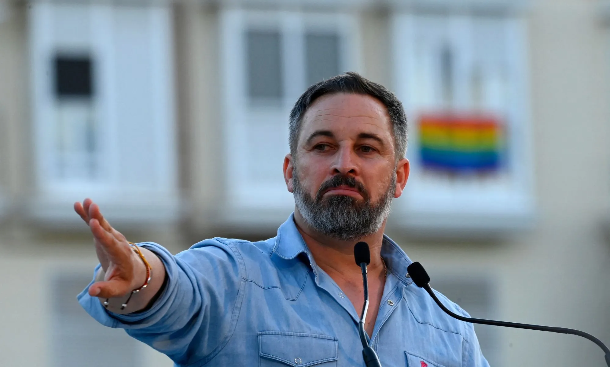 far-right party Vox leader Santiago Abascal holds his hand up during a political rally in Spain ahead of the general election as an LGBTQ+ flag can be seen in the background