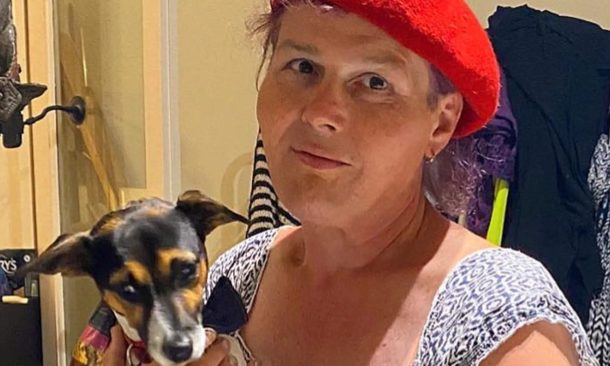 Sarah Jane Baker, in a red cap, holds her dog.