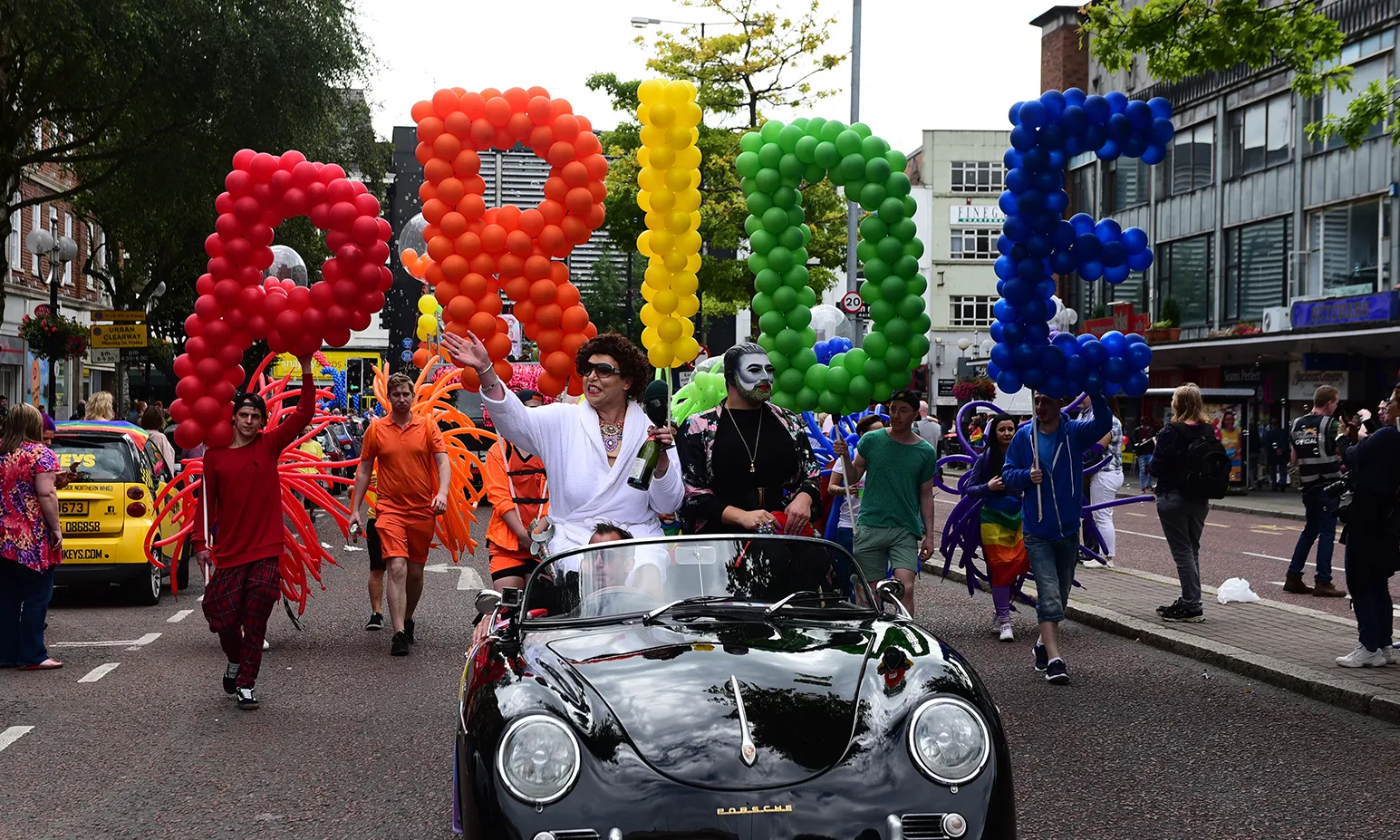 Revellers carry large multi-coloured balloons reading