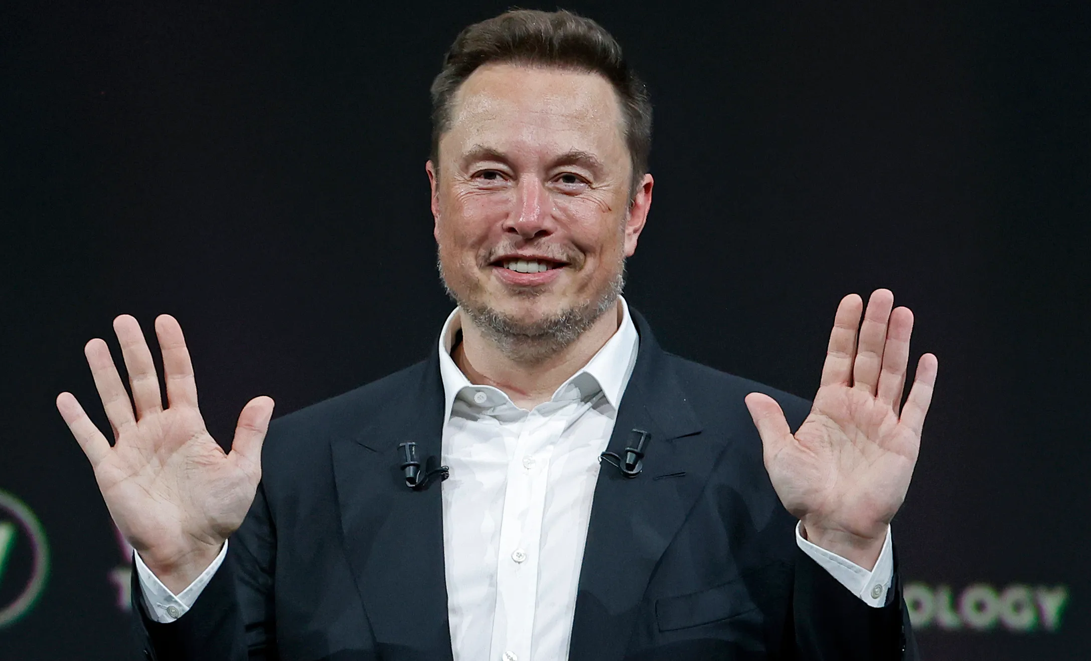 Owner of Twitter Elon Musk sits with his hands up