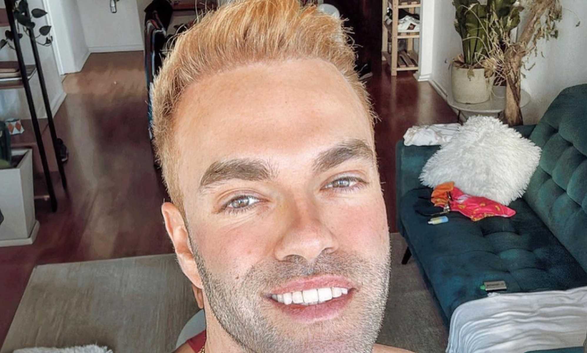 Miguel Alvaro with blonde hair smiles and looks into the camera