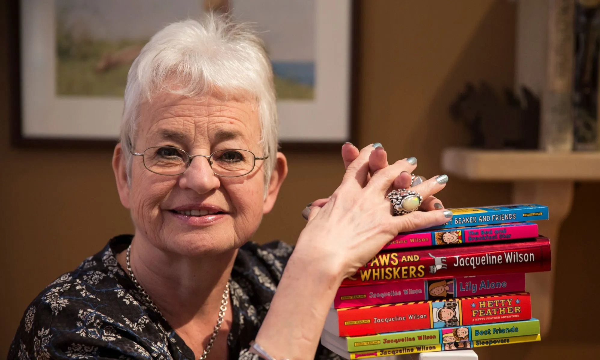 Jacqueline Wilson resting her hands on a pile of her books.