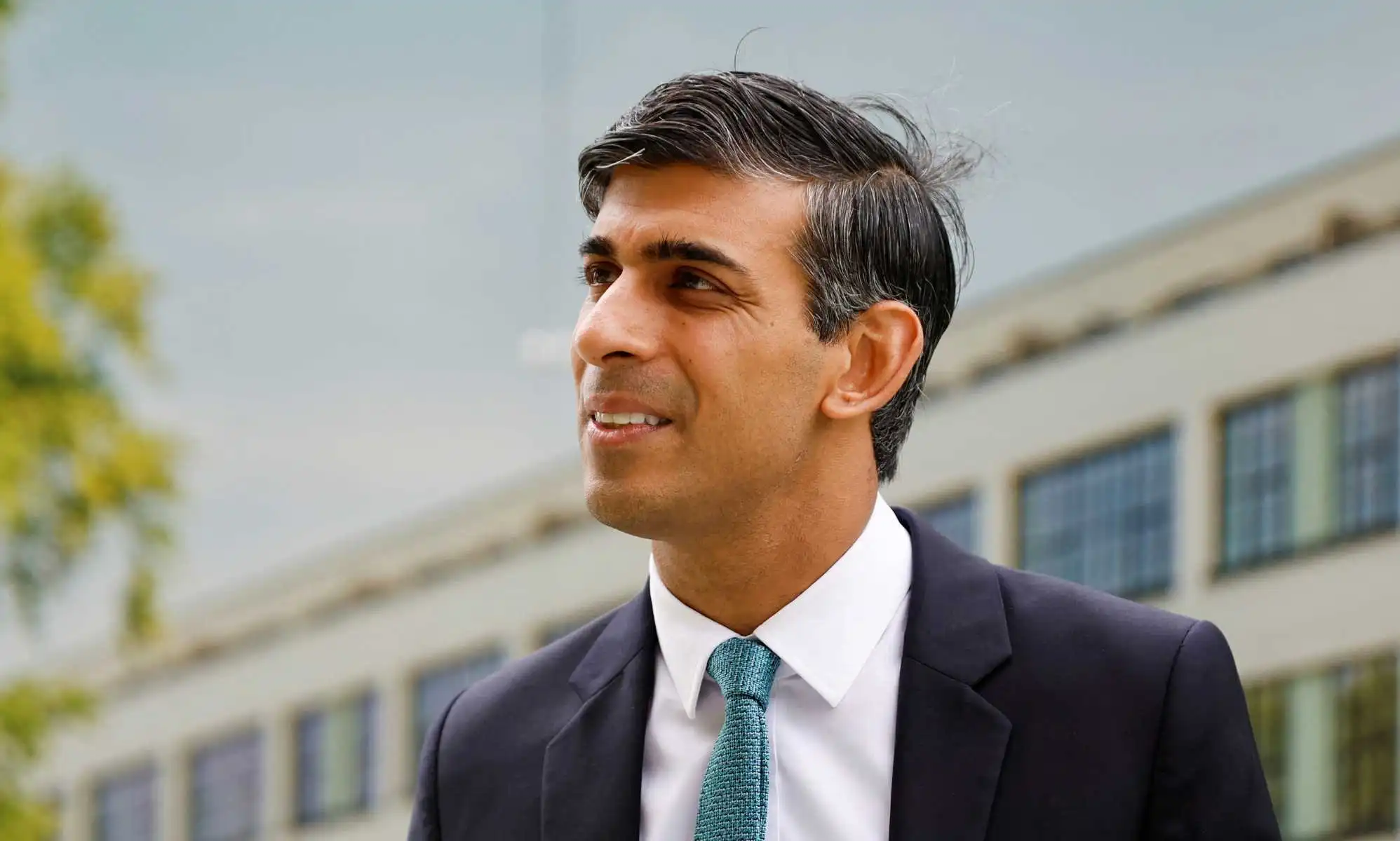 Rishi Sunak pictured outdoors wearing a suit and tie at an event.