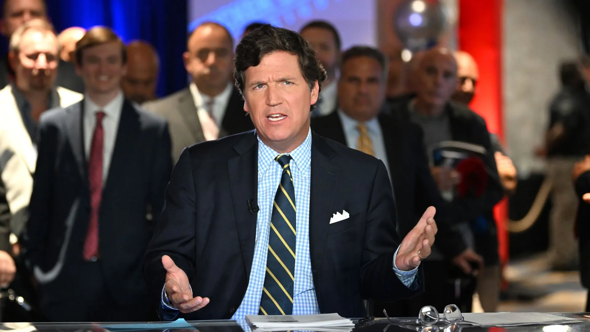 American political commentator Tucker Carlson delivers a talk wearing a suit and tie