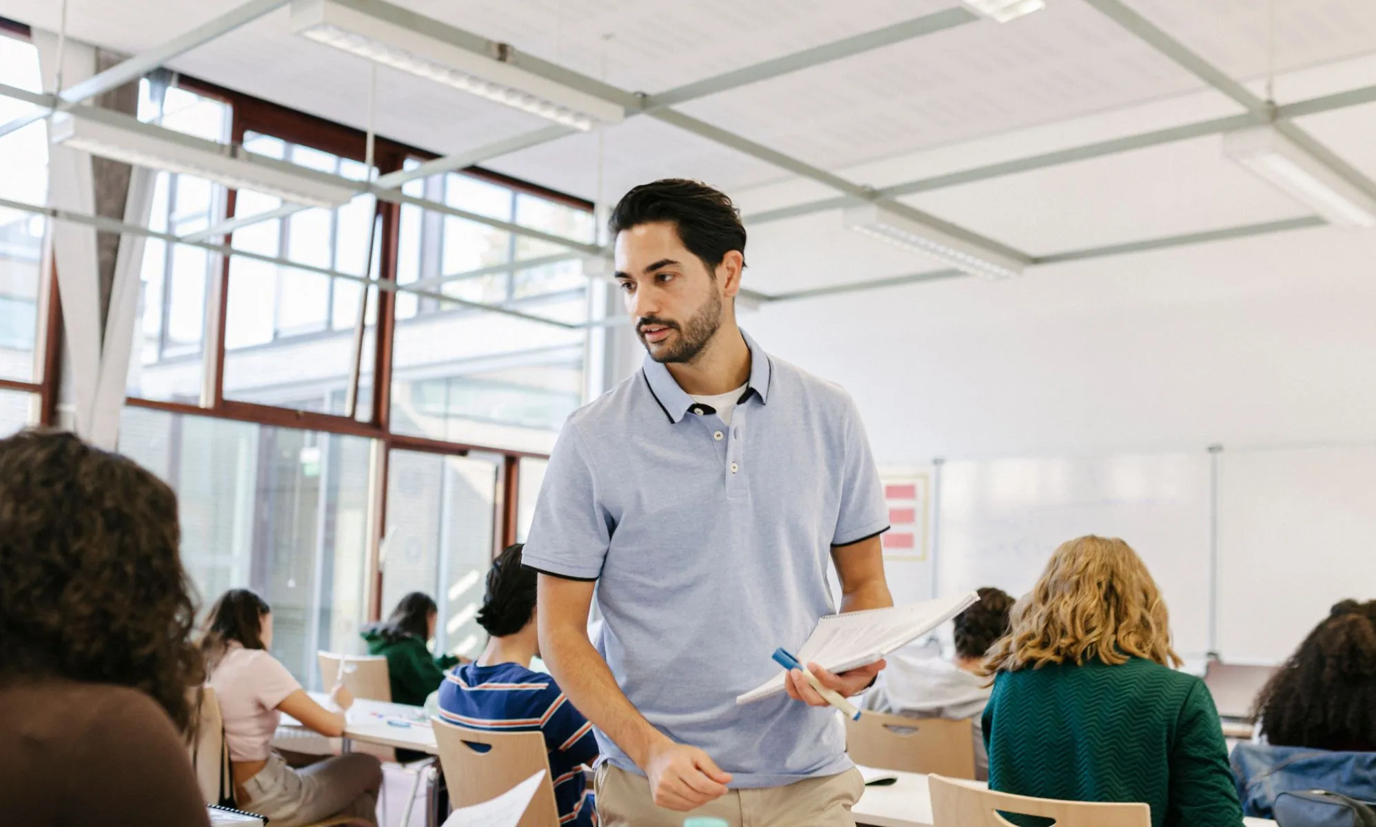Photo of a teacher standing in a classroom surrounded by secondary age students