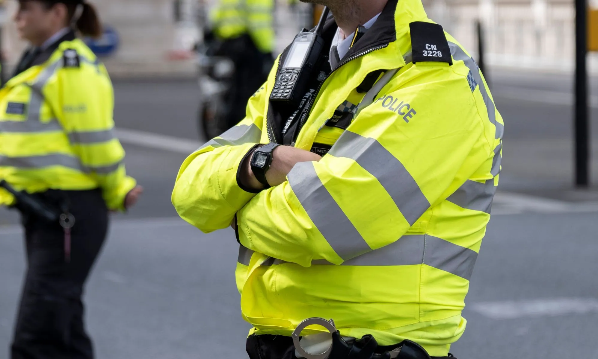 A male Metropolitan Police officer wears yellow reflective gear as he crosses his arms. The force has been accused of fostering a homophobic and sexist environment in the past