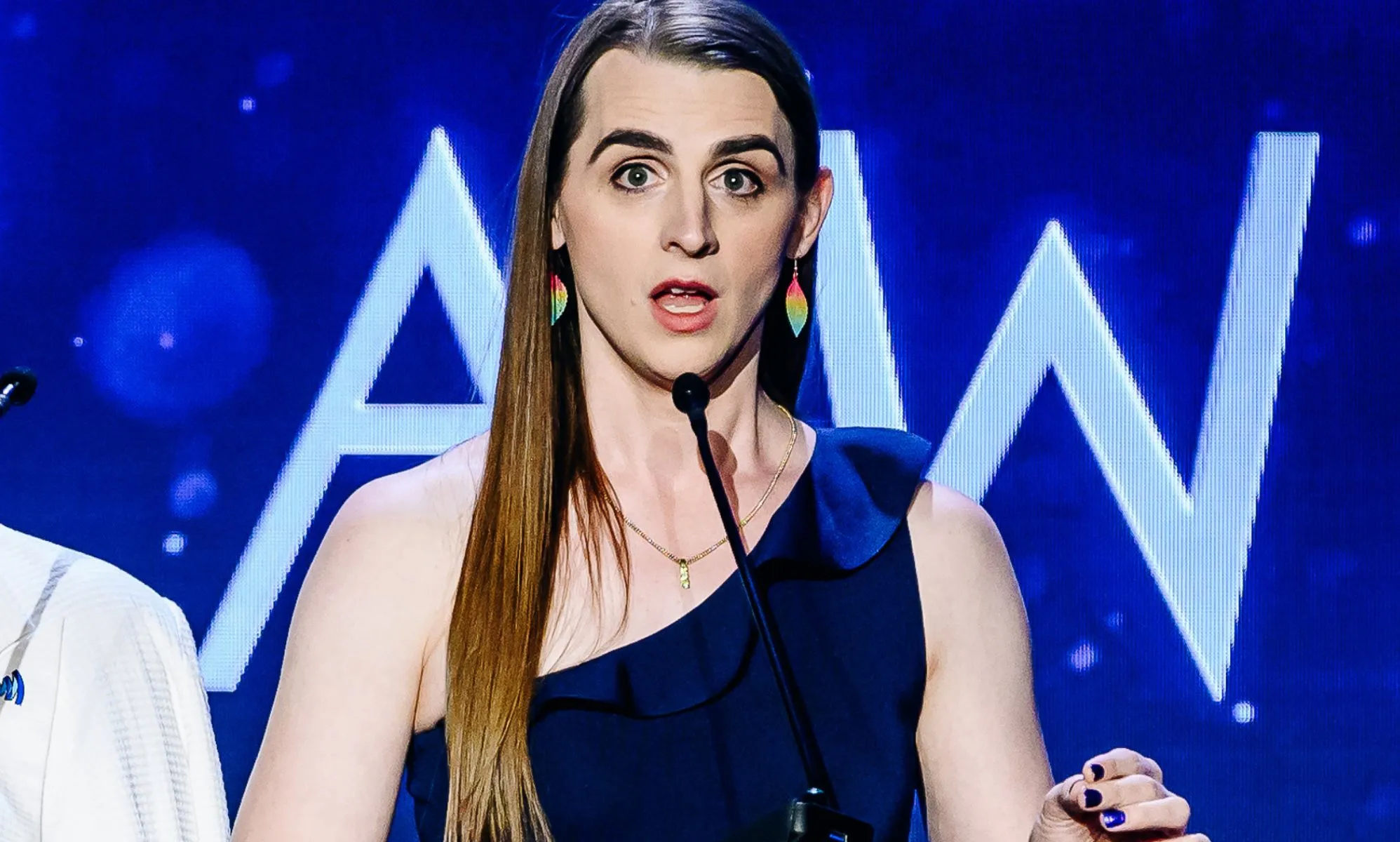 Zooey Zephyr, wearing a single-strap blue dress, speaking during the GLAAD Media Awards.