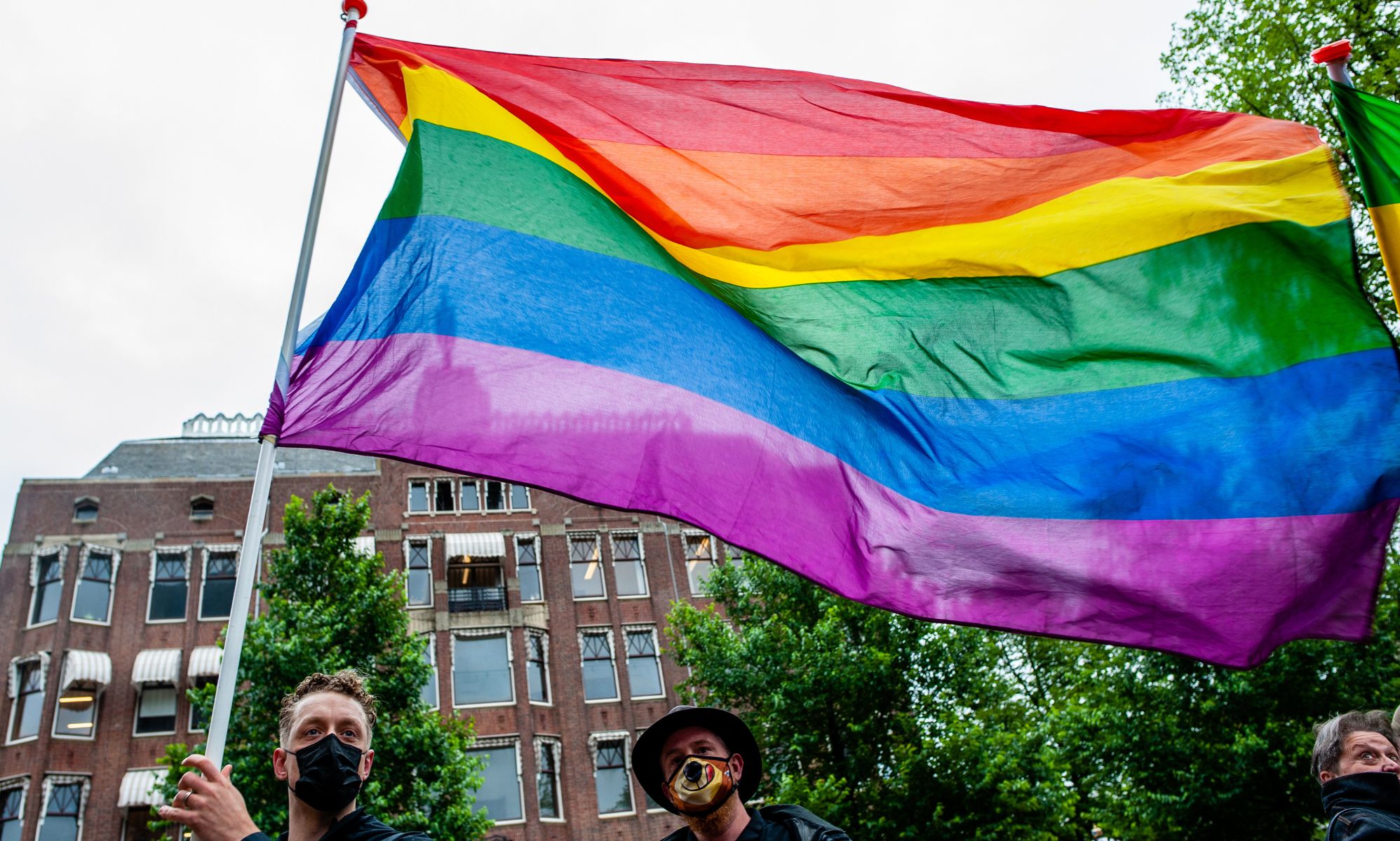 A person holds up a rainbow LGBTQ+ Pride flag