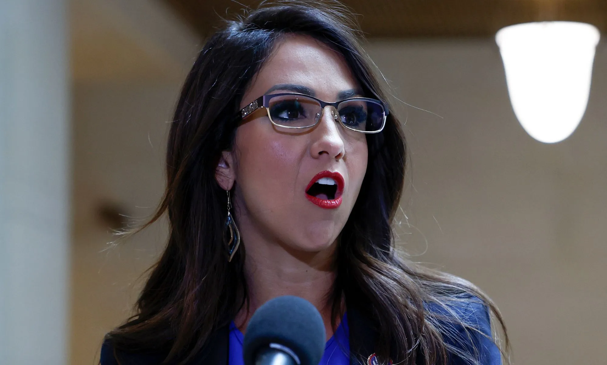 Lauren Boebert speaks into a microphone at a press interview.