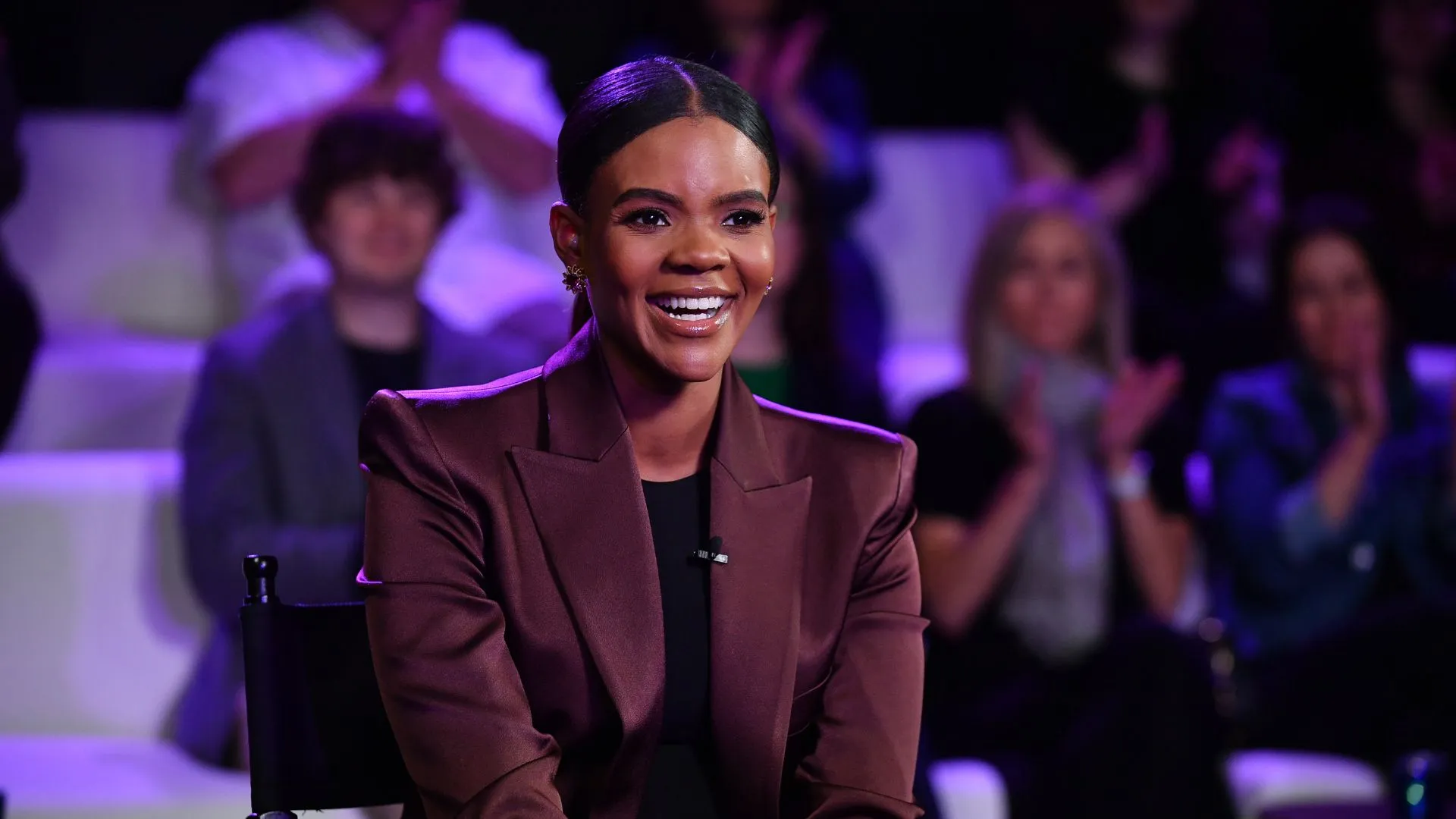 Talk-show host Candace Owens sits on a chair smiling