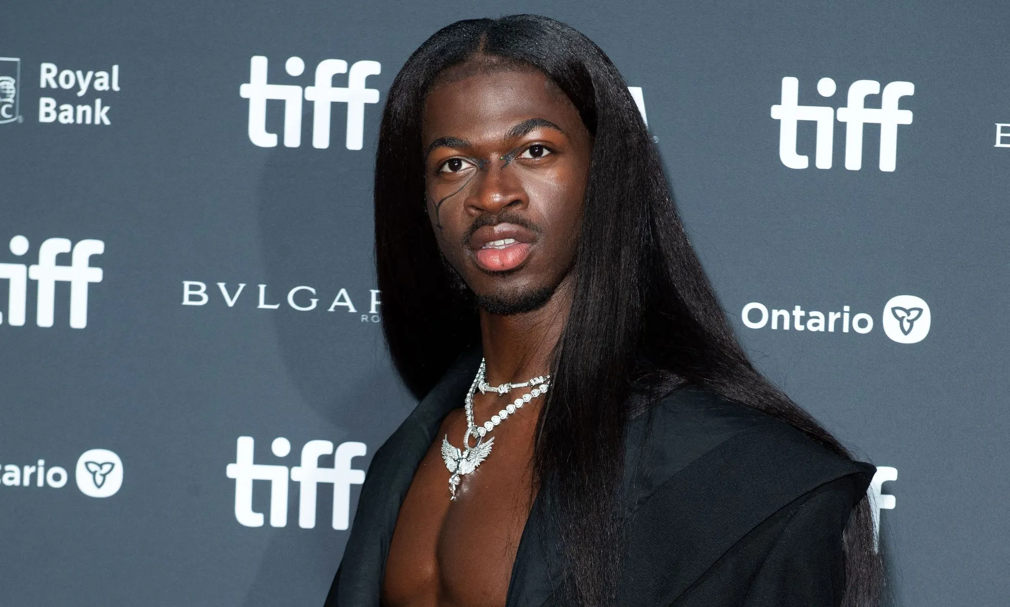 Lil Nas X wears long black hair and a black jacket at the premiere of his documentary, which was delayed because of a bomb threat
