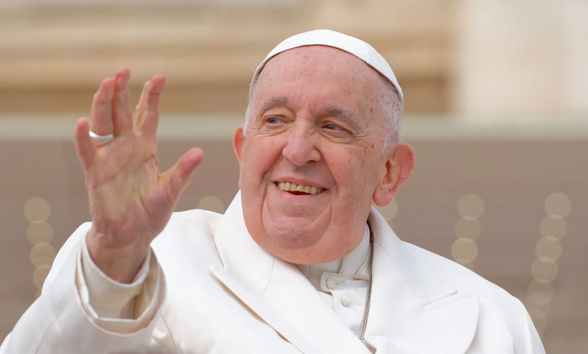 Pope Francis wears a white jacket, white robes and cap as he waves to people gathered in a public audience at the Vatican in Rome