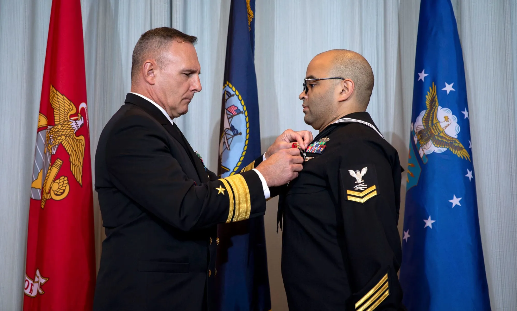 Information Technician 2nd Class Thomas James wears a Naval uniform as a medal is pinned to his chest in a ceremony honouring his brave actions on the night of the Club Q shooting in November 2022