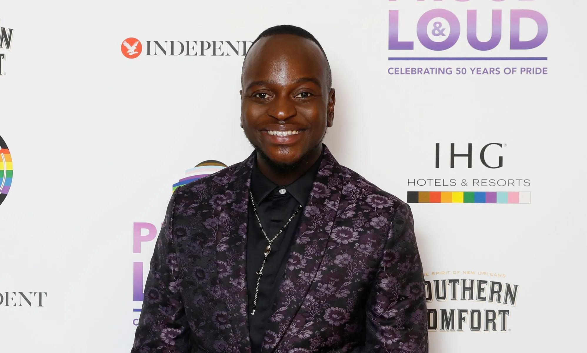 Will Njobvu in a patterned black and purple suit.