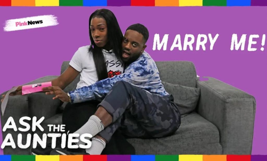 This is an image of two Black men sitting on a couch with a purple background behind them. In text reads