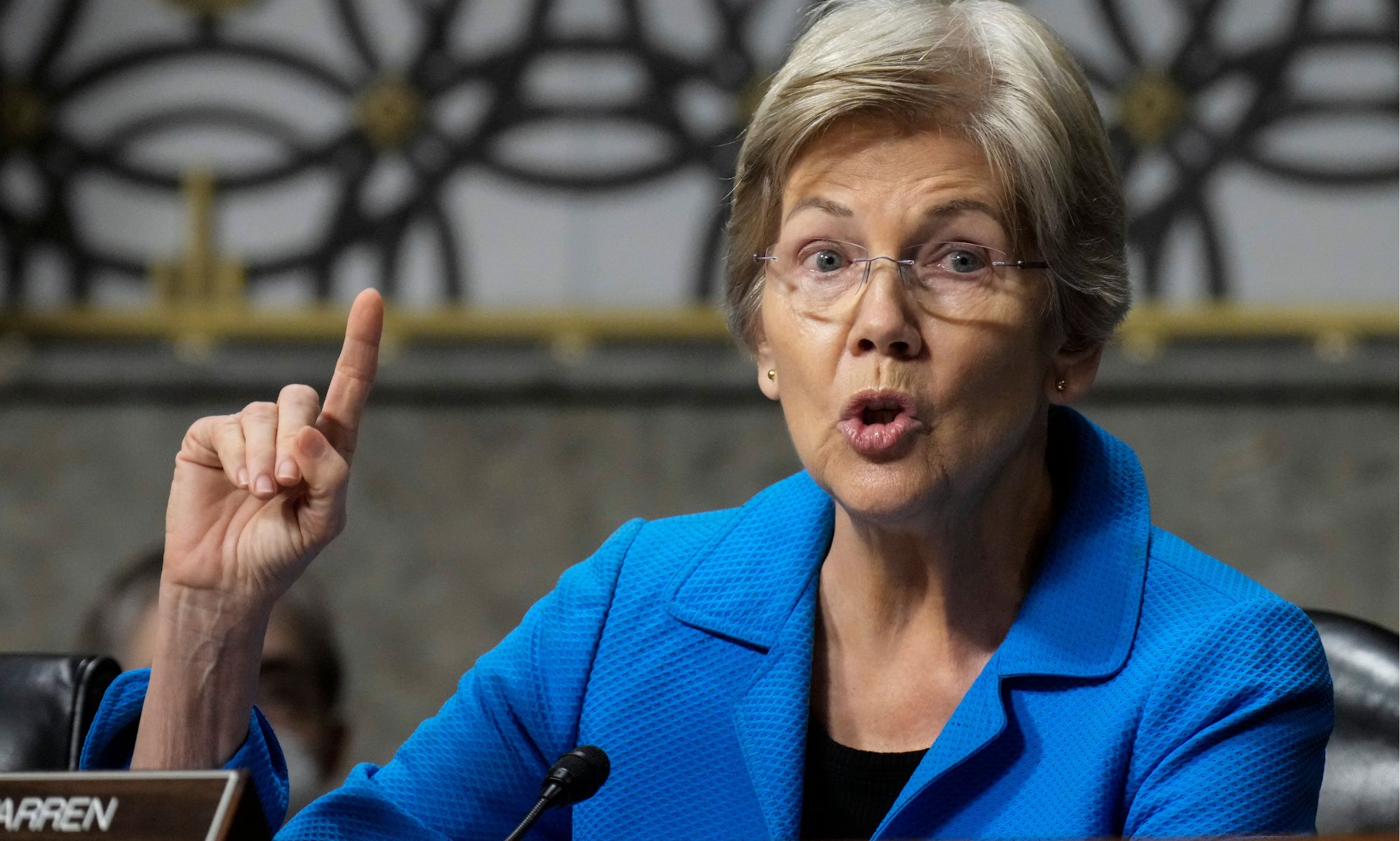Elizabeth Warren raises a finger to enunciate a point while speaking.
