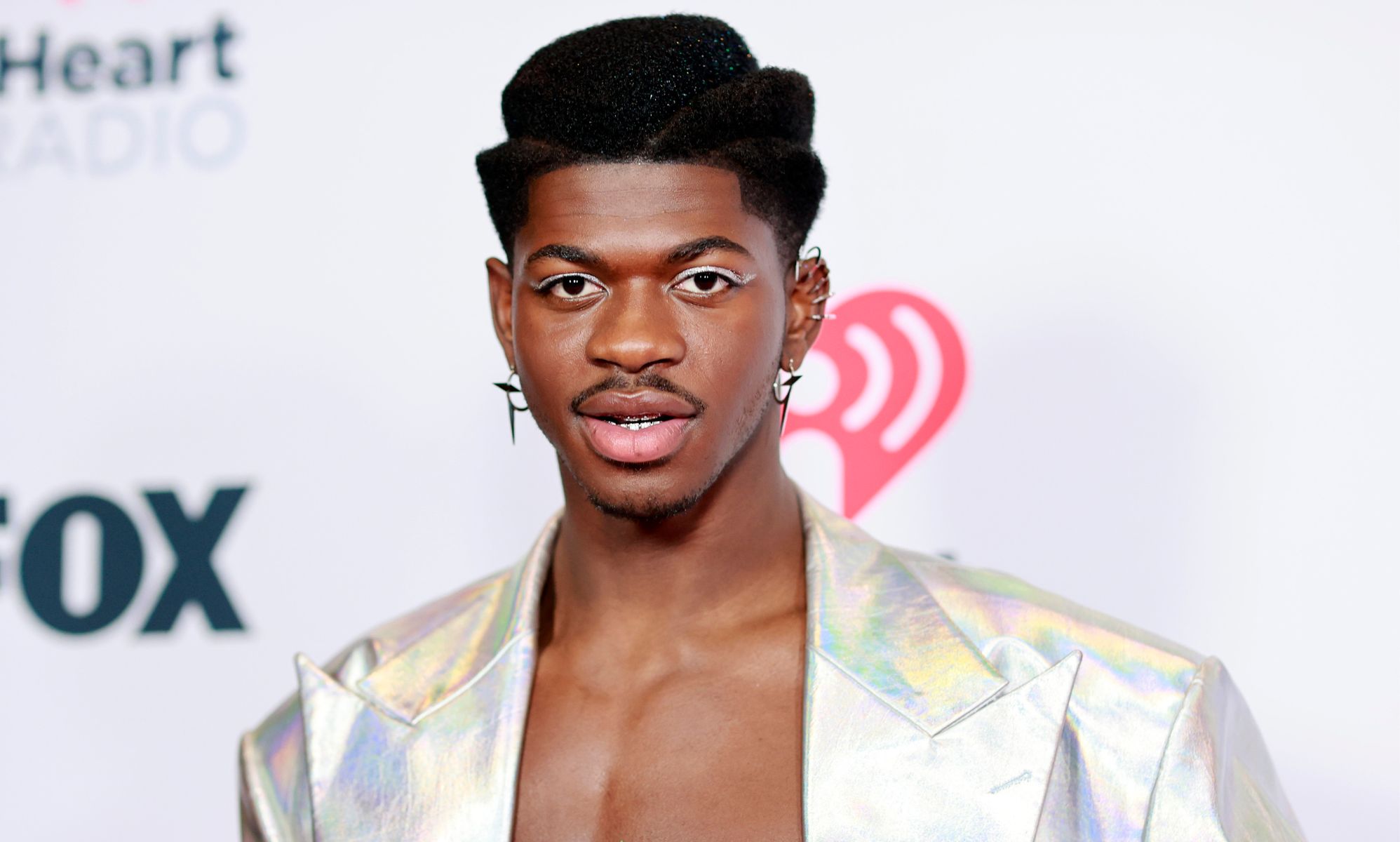 Lil Nas X topless and in a silver jacket.