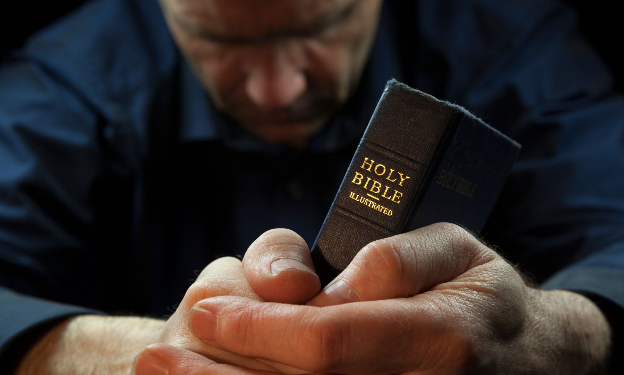 A man prays over a Bible.