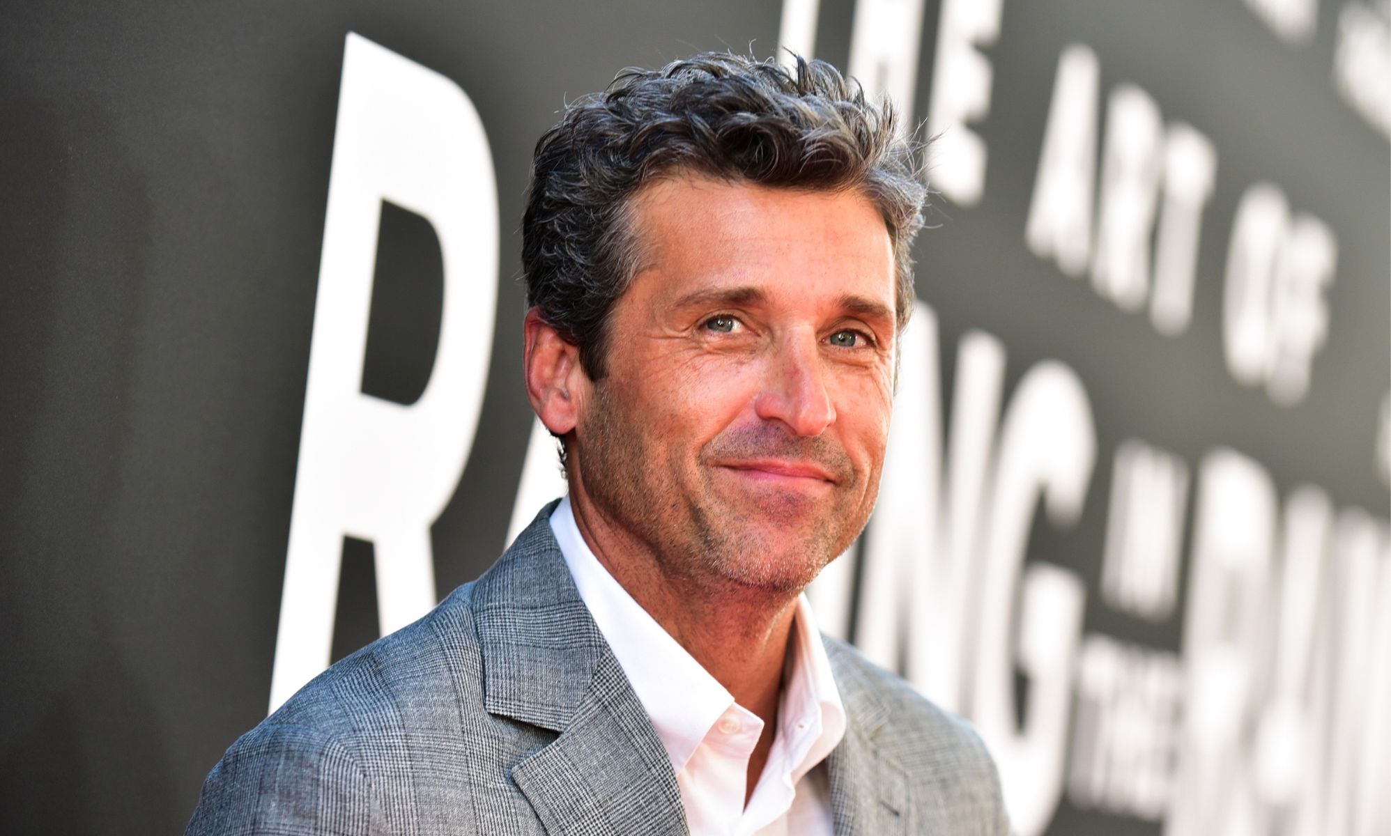 Patrick Dempsey, the Sexiest Man Alive, in a grey suit jacket and white shirt, smiling.