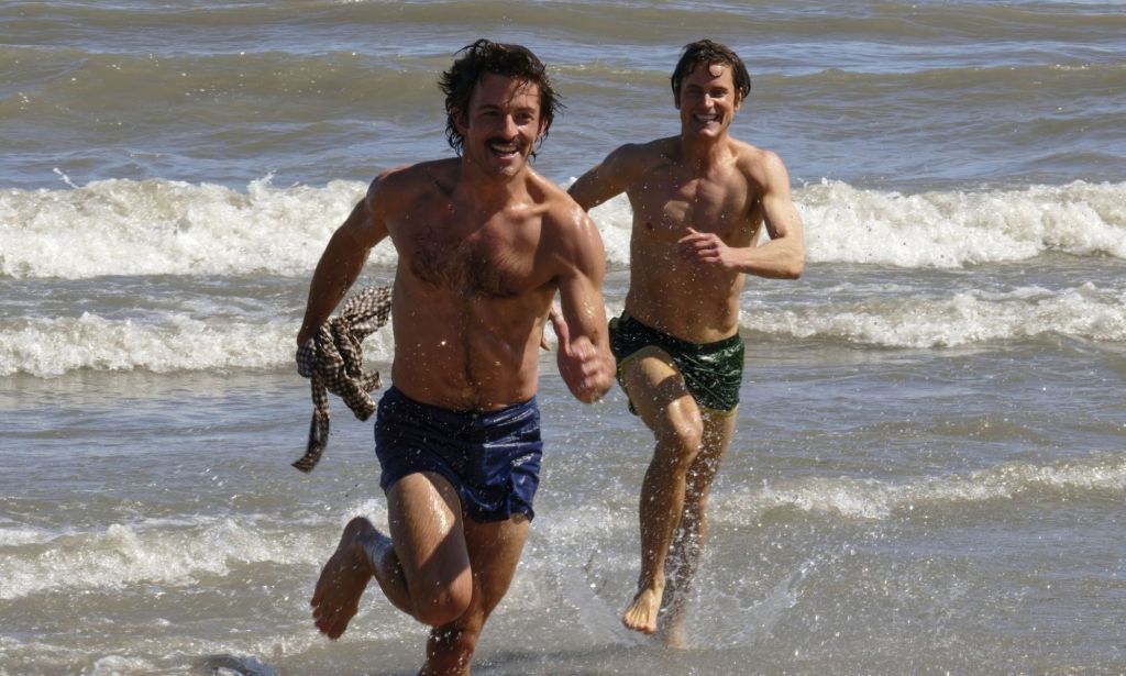 Jonathan Bailey y Matt Bailey se persiguen en una playa en una imagen fija de Compañeros de viaje.
