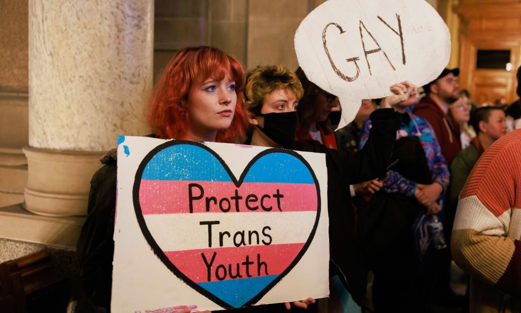 Los manifestantes sostienen un cartel que dice: "Proteger a los jóvenes trans" y "gays" mientras protestan contra los republicanos que atacan los derechos LGBTQ+, incluida la educación sobre temas queer y la atención médica trans.