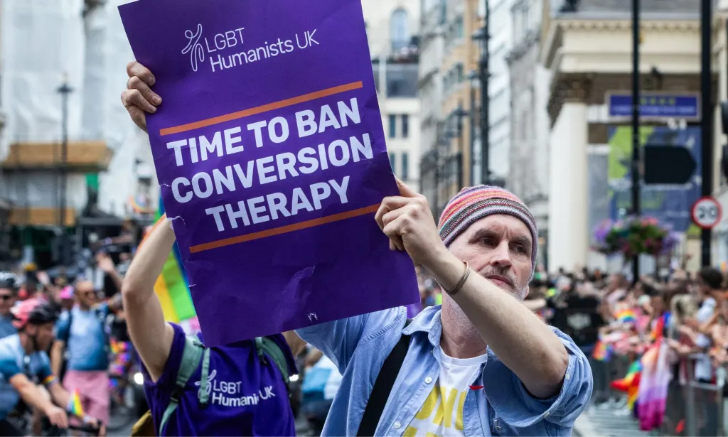Un manifestante sostiene un cartel que dice "es hora de prohibir la terapia de conversión".