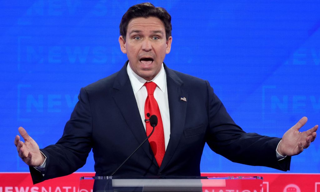 GOP presidential hopeful Ron DeSantis wears a suit and tie as he stands at a podium for the Republican debate, where he made several anti-trans statements