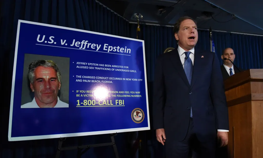 Una fotografía de un abogado, vestido con traje y corbata, parado frente al tablero que detalla los cargos contra Jeffrey Epstein.