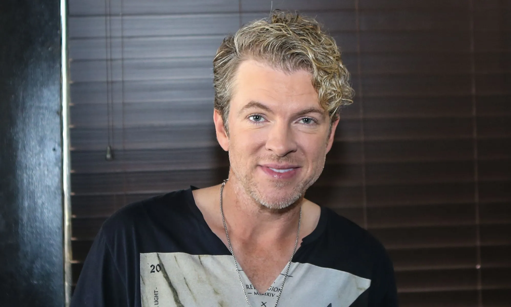 Joe Don Rooney smiling in a black and grey top.