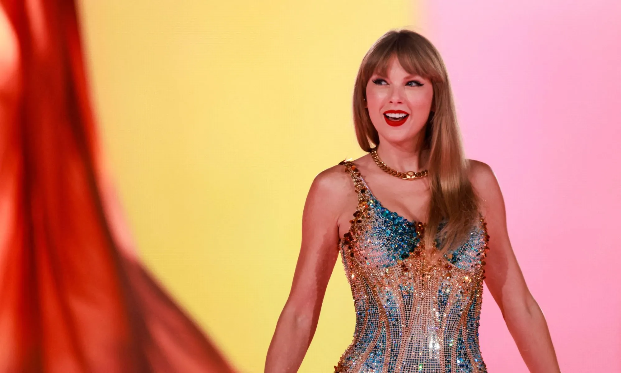 Taylor Swift wears a sparkly outfit as she poses with her arms out during a concert