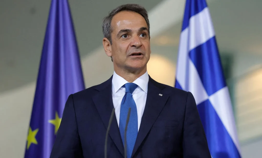 Kyriakos Mitsotakis infront of a Greece and European Union flag.