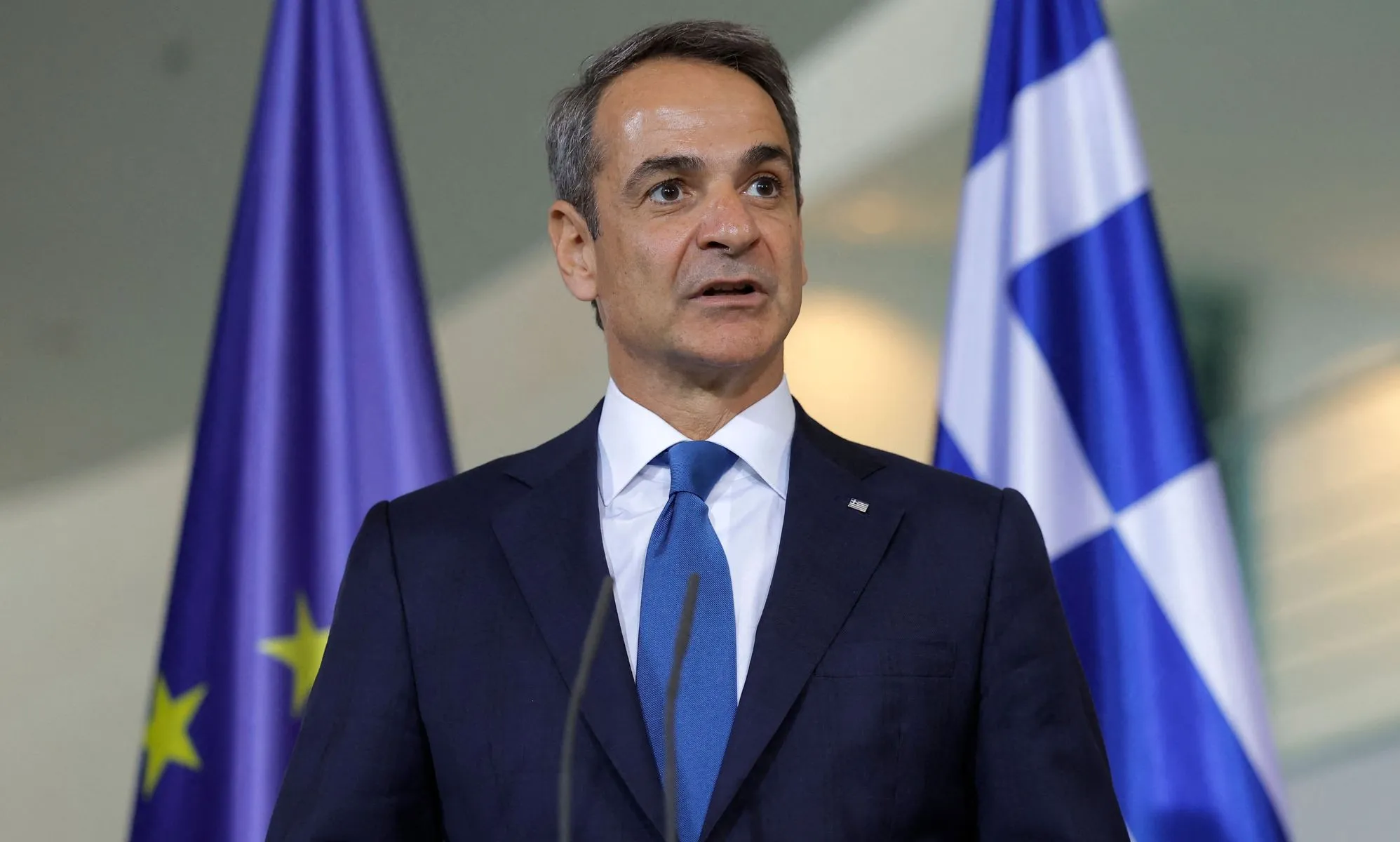 Kyriakos Mitsotakis infront of a Greece and European Union flag.