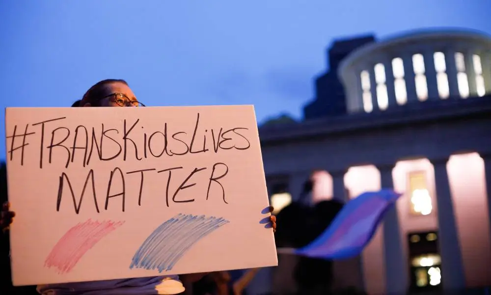 A transgender rights advocate holds a sign that reads