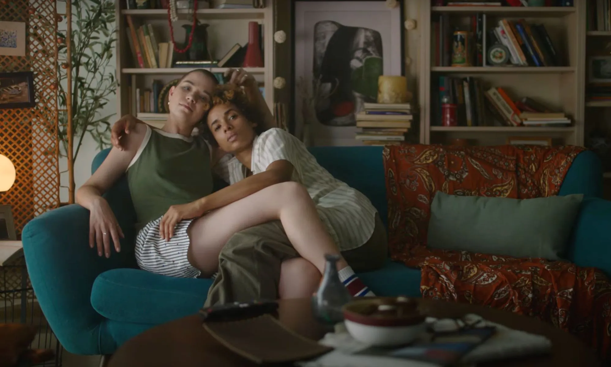 Screenshot of an eHarmony advert shows queer couple sitting together on a sofa hugging