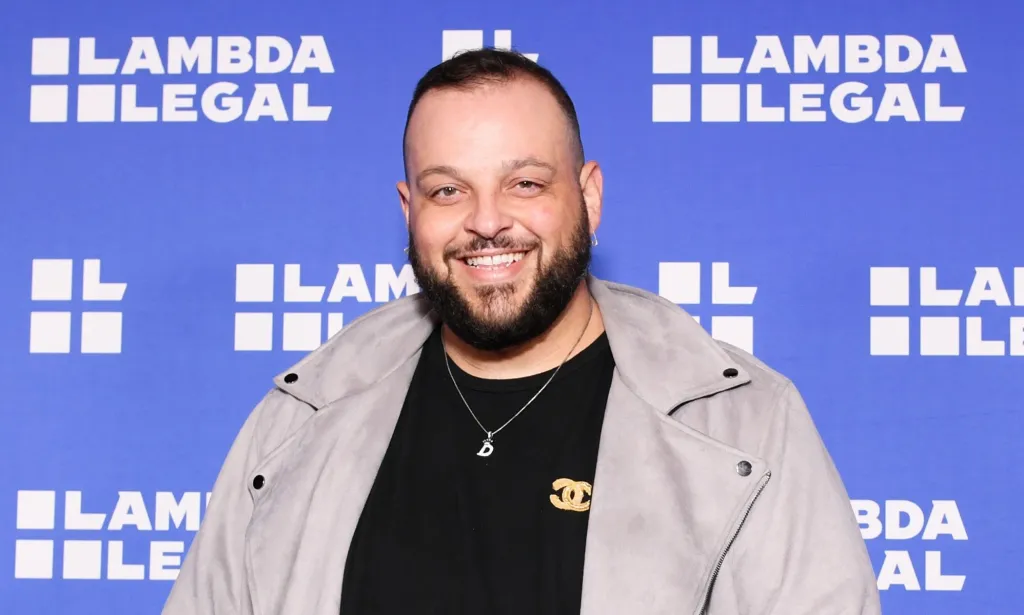 La estrella de Mean Girls, Daniel Franzese, con una camisa negra y una chaqueta gris.