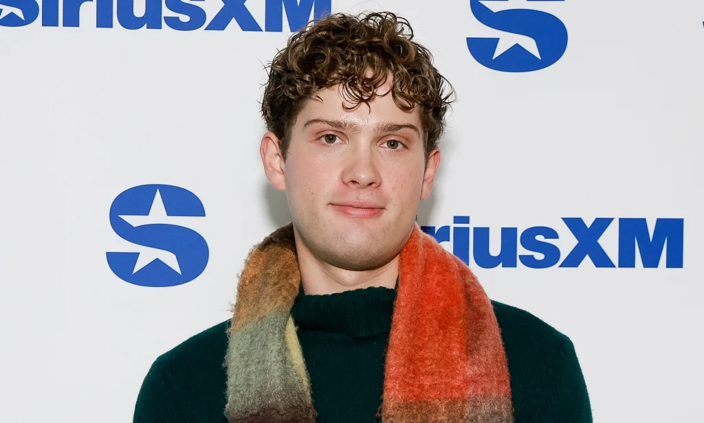 Leo Reich, a curly haired man with a slightly fluffy red, yellow and blue scarf, he