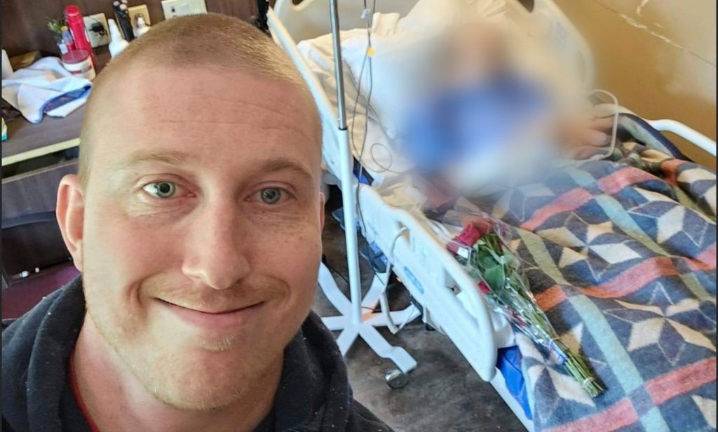 A picture of Bubba Pollock standing in front of a hospitalised man, blurred out