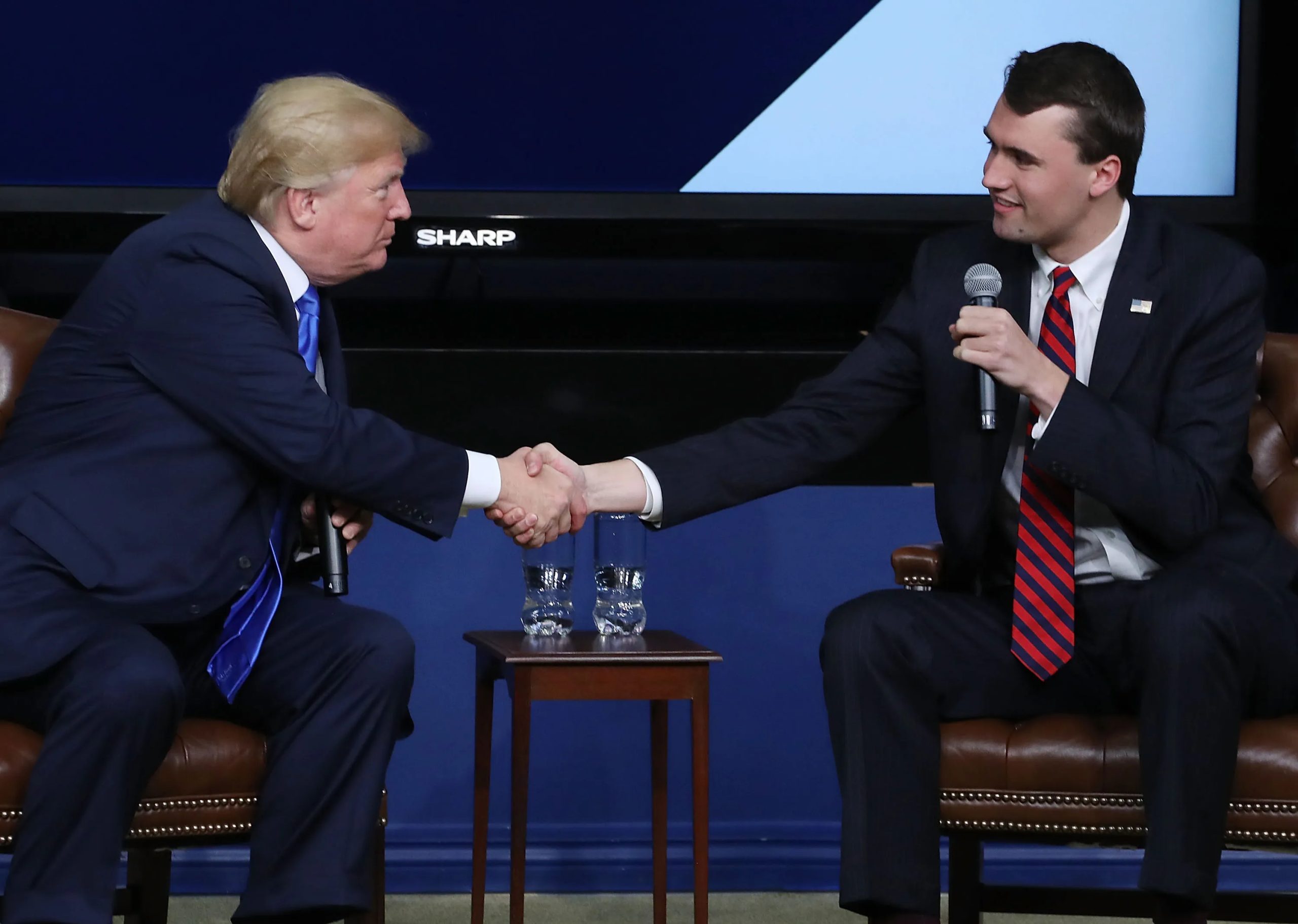 Image shows far right activist Charlie Kirk shaking hands with Donald Trump