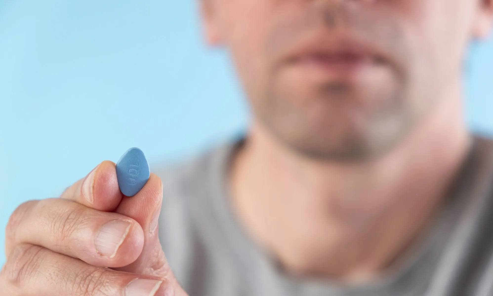 man holding a blue erectile dysfuncrtion viagra pill