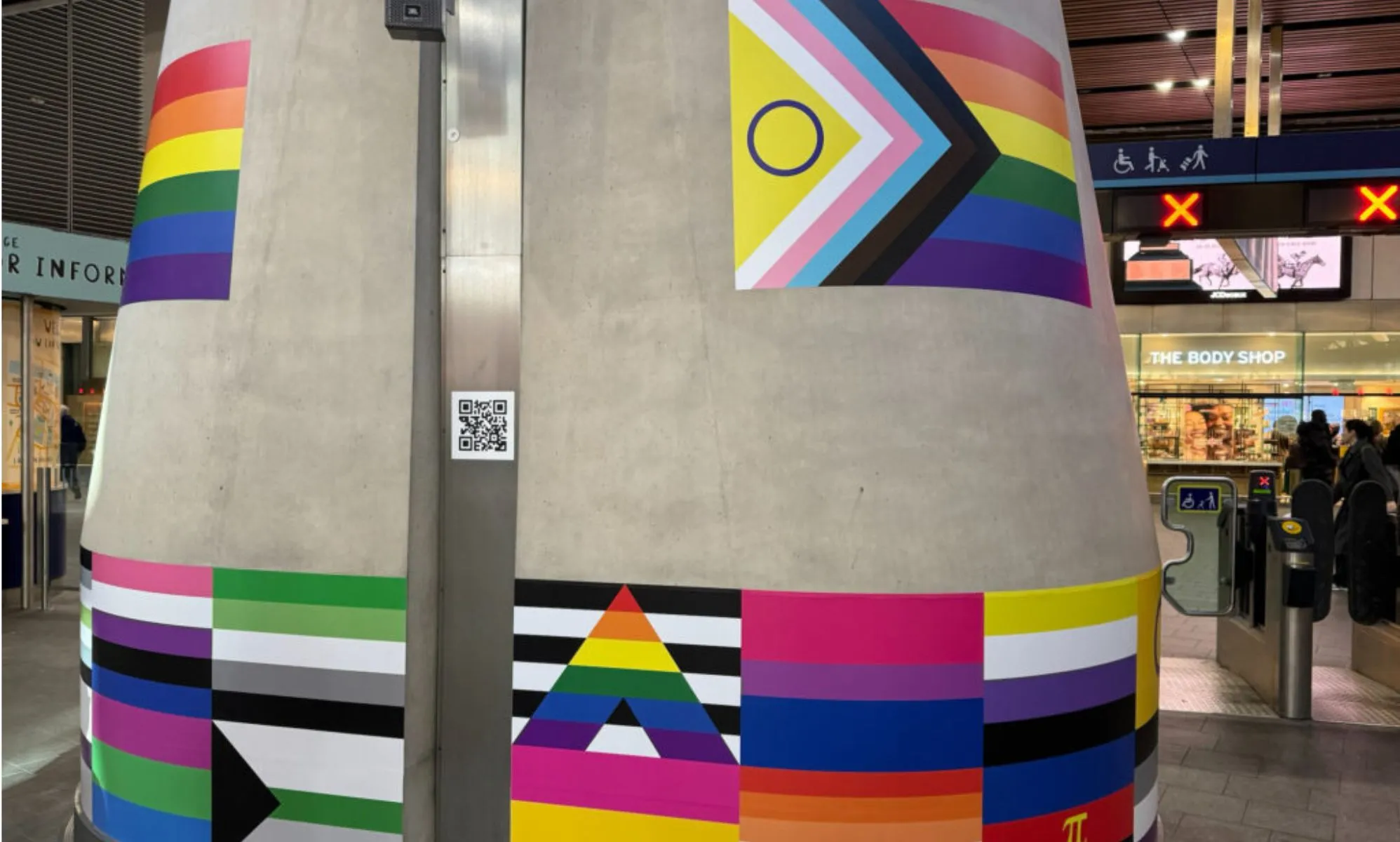 A pillar with stickers of LGBTQ+ flags across it at London Bridge station marking LGBT+ History Month
