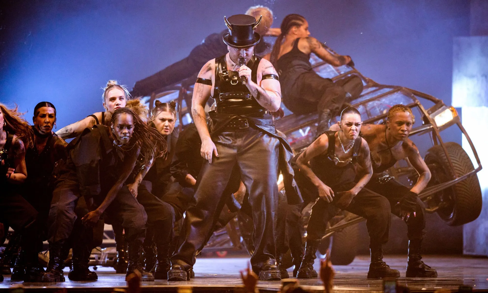 Sam Smith wears a horned top hat while they sing surrounded by backup dancers during a performance of their song