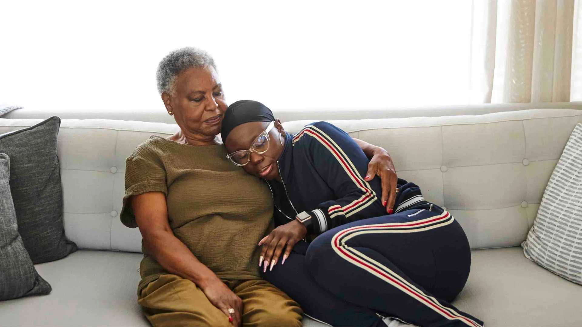Stock image illustrating cancer shows woman wearing headscarf hugging her mother on the sofa