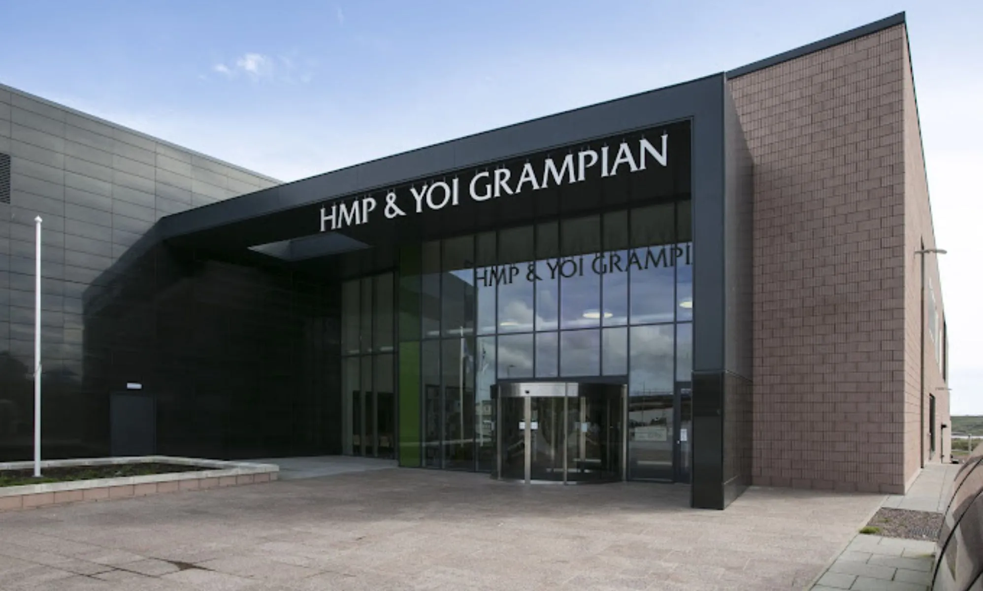 The front of the HMP Grampian, with glass pane windows and a brick building.