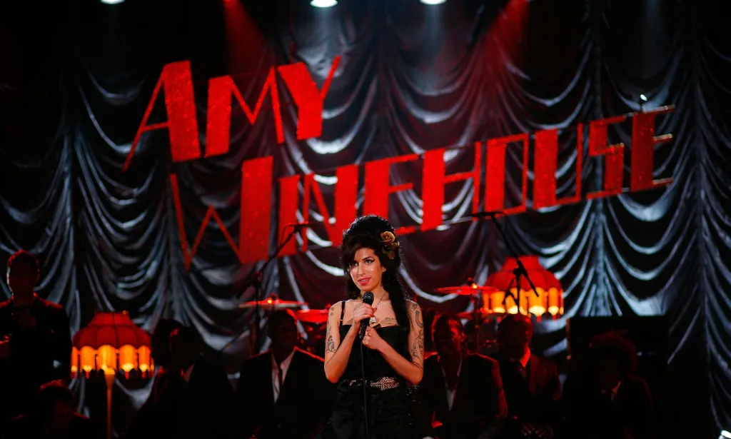 Amy Winehouse actúa frente a un cartel rojo que dice Amy Winehouse.